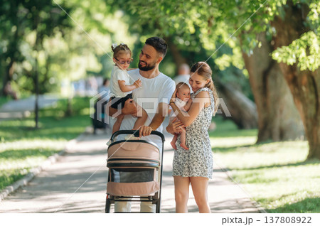 Baby is in hands. Couple is with daughter, newborn baby and cradle are having a walk 137808922