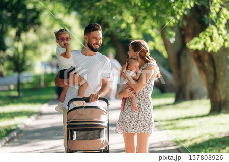 Baby is in hands. Couple is with daughter, newborn baby and cradle are having a walk 137808926