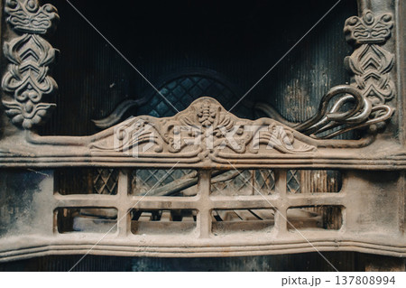 Old iron fireplace with decorative fireguard range and fireplace accessories. Fireplace poker and scoop in vintage metal fireplace. Clean fireplace with soot and forged steel. Firewood grates closeup 137808994