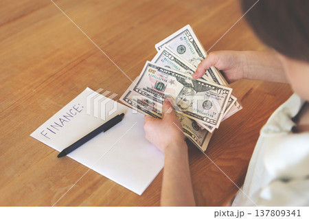 Wealthy kid holding large fan of dollar bills next to finance note, rich child with lots of cash, money and wealth concept, financial success indoors close-up 137809341