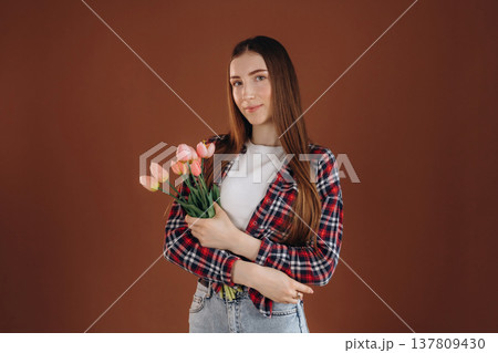 Flowers in hands, conception of gift, present, holidays. Woman in casual clothes is against background Flowers in hands, conception of gift, present, holidays. Woman in casual clothes is against background 137809430