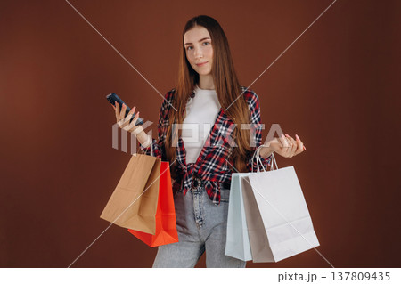Shopping bags, smartphone. Woman in casual clothes is against background Shopping bags, smartphone. Woman in casual clothes is against background 137809435
