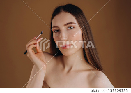 Make up, cosmetics conception. Young woman is against background Make up, cosmetics conception. Young woman is against background 137809523
