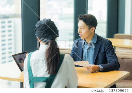 カフェで働く女性と打ち合わせるスーツの男性　 137809692