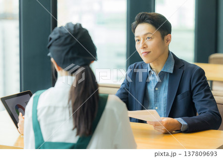 カフェで働く女性と打ち合わせるスーツの男性　 137809693