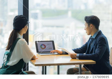 カフェで働く女性と打ち合わせるスーツの男性 カフェで働く女性と打ち合わせるスーツの男性 137809695
