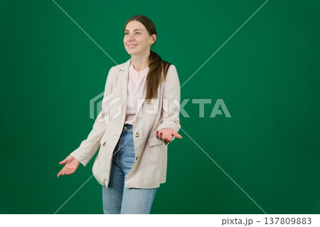 Various emotions and poses of a woman in a beige jacket and jeans, wearing a pink European T-shirt with her hair pulled back into a ponytail, against a green background 137809883