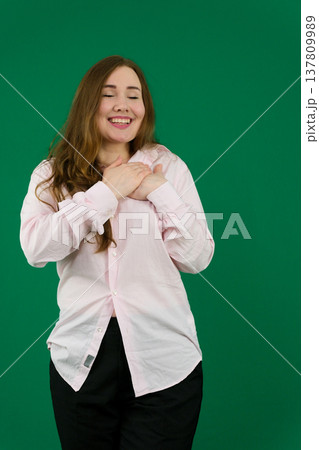 Various emotions and movements of a woman in a pink shirt and black pants on a green background. A European woman with a round face. Various poses. Various emotions and movements of a woman in a pink shirt and black pants on a green background. A European woman with a round face. Various poses. 137809989