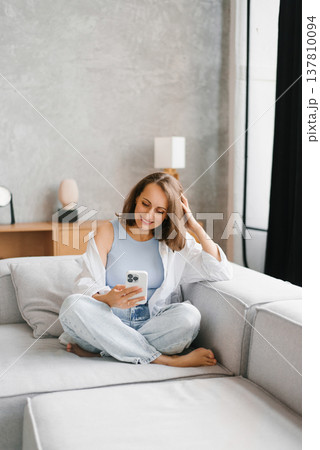 Happy Woman Sitting Cross Legged With Smartphone Happy Woman Sitting Cross Legged With Smartphone 137810094