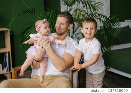 Father Sitting On Sofa With Young Son And Daughter 137810099