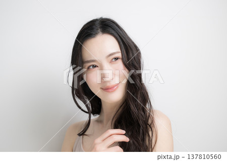 白背景に綺麗な黒髪をなびかせるロングヘアでパーマの女性 ヘアケアやトリートメントイメージ 白背景に綺麗な黒髪をなびかせるロングヘアでパーマの女性 ヘアケアやトリートメントイメージ 137810560
