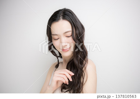 黒髪をなびかせるロングヘアでパーマの女性　ヘアケアやトリートメントイメージ目を閉じる 137810563