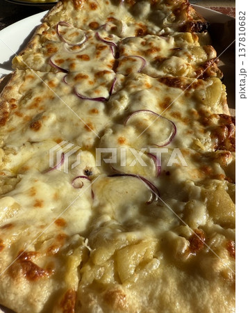 Close-up of cheesy pizza with red onion and pineapple slices viewed in warm lighting background Close-up of cheesy pizza with red onion and pineapple slices viewed in warm lighting background 137810682