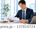 オフィスデスクで書類を確認する男性エグゼクティブ 137810724
