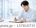 オフィスデスクで手帳に予定を書き込む男性会社員 137810735