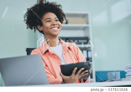 Smiling businesswoman working on laptop in office 137811026
