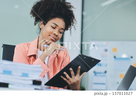 Smiling businesswoman working on laptop in office Smiling businesswoman working on laptop in office 137811027