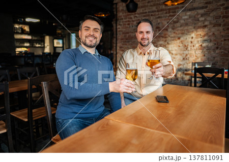 Friends toasting beer glasses celebrating at bar Friends toasting beer glasses celebrating at bar 137811091