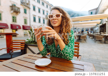 Happy woman sitting by table drinking coffee of outdoor sidewalk cafe restaurant, on summer day. Happy woman sitting by table drinking coffee of outdoor sidewalk cafe restaurant, on summer day. 137811251