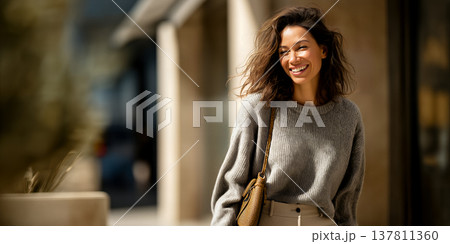 Energetic woman with curly hair smiling as she explores busy city shopping district 137811360