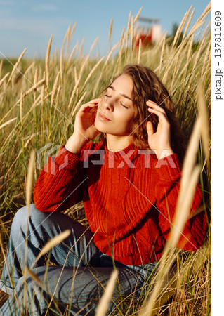 Beautiful young woman enjoying nature outdoors in tall grass. Flying hairs. Lifestyle. Fashion style Beautiful young woman enjoying nature outdoors in tall grass. Flying hairs. Lifestyle. Fashion style 137811609