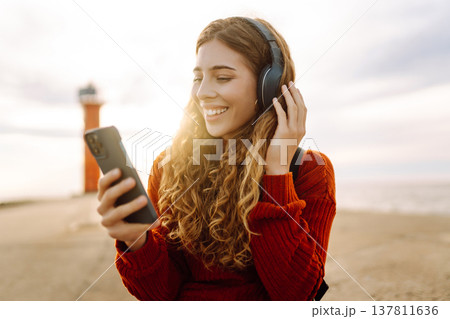 Relaxed woman enjoying music by the waterfront while wearing headphone. Travel and blogging concept 137811636