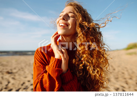 Portrait of a beautiful woman on the beach at sunset at the windy autumn day. Fashion style. Travel 137811644
