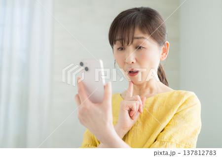 スマホを操作する60代女性 137812783