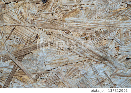 A horizontal close-up shot of a rough oriented strand board (OSB) surface with visible wood flakes and chips. 137812991