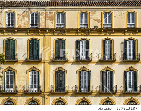 Sunlit Yellow Historic Facade With Shuttered Windows and Wrought Iron Balconies, Mediterranean Style Sunlit Yellow Historic Facade With Shuttered Windows and Wrought Iron Balconies, Mediterranean Style 137813187