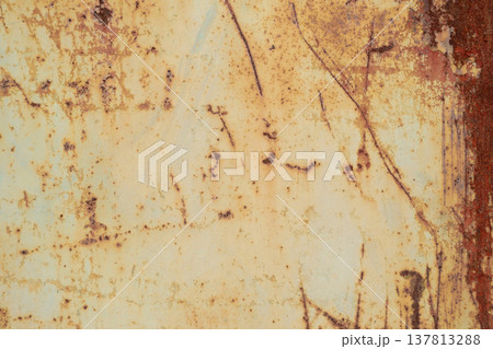 A horizontal close-up shot of a heavily weathered metal surface with deep rust, scratches, and remains of yellowish paint. A horizontal close-up shot of a heavily weathered metal surface with deep rust, scratches, and remains of yellowish paint. 137813288