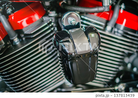 A detailed horizontal macro shot of a motorcycle engine featuring a combination of glossy black components, polished metal details, and vibrant red cylinder head covers. 137813439