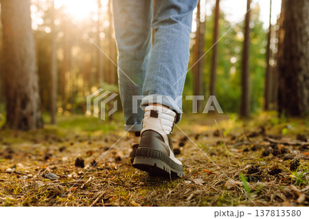 Hiker's boots stepping on a blanket of fallen autumnal orange leaves in the forest. Travel Hiker's boots stepping on a blanket of fallen autumnal orange leaves in the forest. Travel 137813580