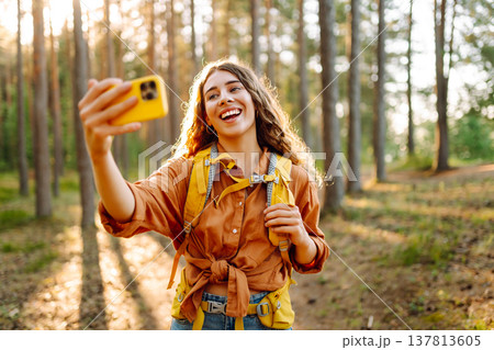 Selfie in nature. Beautiful woman taking picture of herself while walking in a sunny forest. Selfie in nature. Beautiful woman taking picture of herself while walking in a sunny forest. 137813605