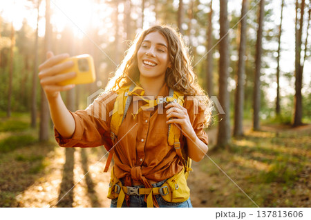 Selfie in nature. Beautiful woman taking picture of herself while walking in a sunny forest. Selfie in nature. Beautiful woman taking picture of herself while walking in a sunny forest. 137813606