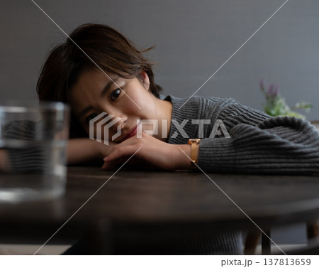 テーブルに頬杖をつく女性の顔 137813659