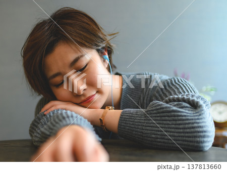 イヤホンで音楽を聴きながらうたた寝する女性 イヤホンで音楽を聴きながらうたた寝する女性 137813660