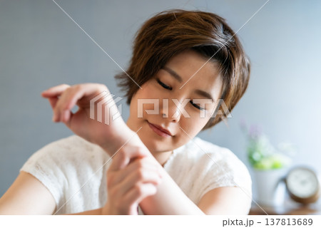 手首のバンドを優しく触る女性の顔 手首のバンドを優しく触る女性の顔 137813689