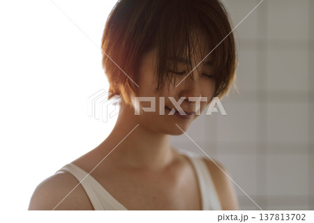 うつむき穏やかに微笑む女性の顔 137813702