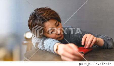 机に突っ伏して眠る女性 137813717