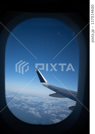 飛行機の窓から望む青い空と広がる雲海、そして機体の翼 137814680