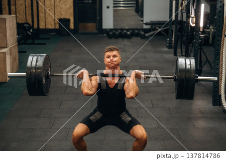 Strong arms and back. Athletic man performing weightlifting exercises with a barbell in a gym Strong arms and back. Athletic man performing weightlifting exercises with a barbell in a gym 137814786