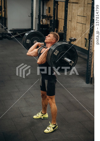 Professional occupation. Athletic man performing weightlifting exercises with a barbell in a gym Professional occupation. Athletic man performing weightlifting exercises with a barbell in a gym 137814799