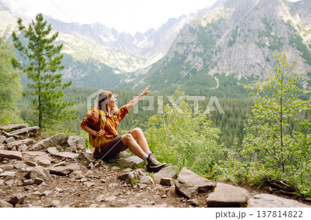 Young traveler woman with a yellow backpack on a cliff. Sports concept, traveler. Active lifestyle. Young traveler woman with a yellow backpack on a cliff. Sports concept, traveler. Active lifestyle. 137814822