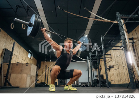 The training process. Athletic man performing weightlifting exercises with a barbell in a gym 137814826