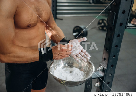 Preparing for competition. Fitness man is rubbing his hands with chalk, specifically magnesium carbonate 137814863