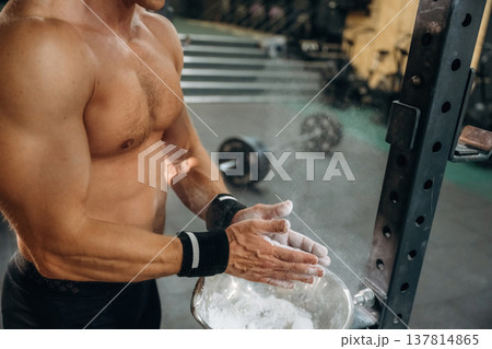 Preparing for competition. Fitness man is rubbing his hands with chalk, specifically magnesium carbonate 137814865