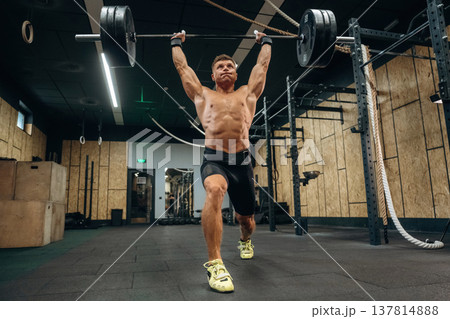 Workout session. Athletic man performing weightlifting exercises with a barbell in a gym 137814888