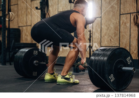 Preparing to do this. Athletic man performing weightlifting exercises with a barbell in a gym Preparing to do this. Athletic man performing weightlifting exercises with a barbell in a gym 137814968