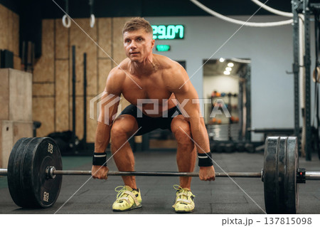 Using quality equipment. Athletic man performing weightlifting exercises with a barbell in a gym Using quality equipment. Athletic man performing weightlifting exercises with a barbell in a gym 137815098